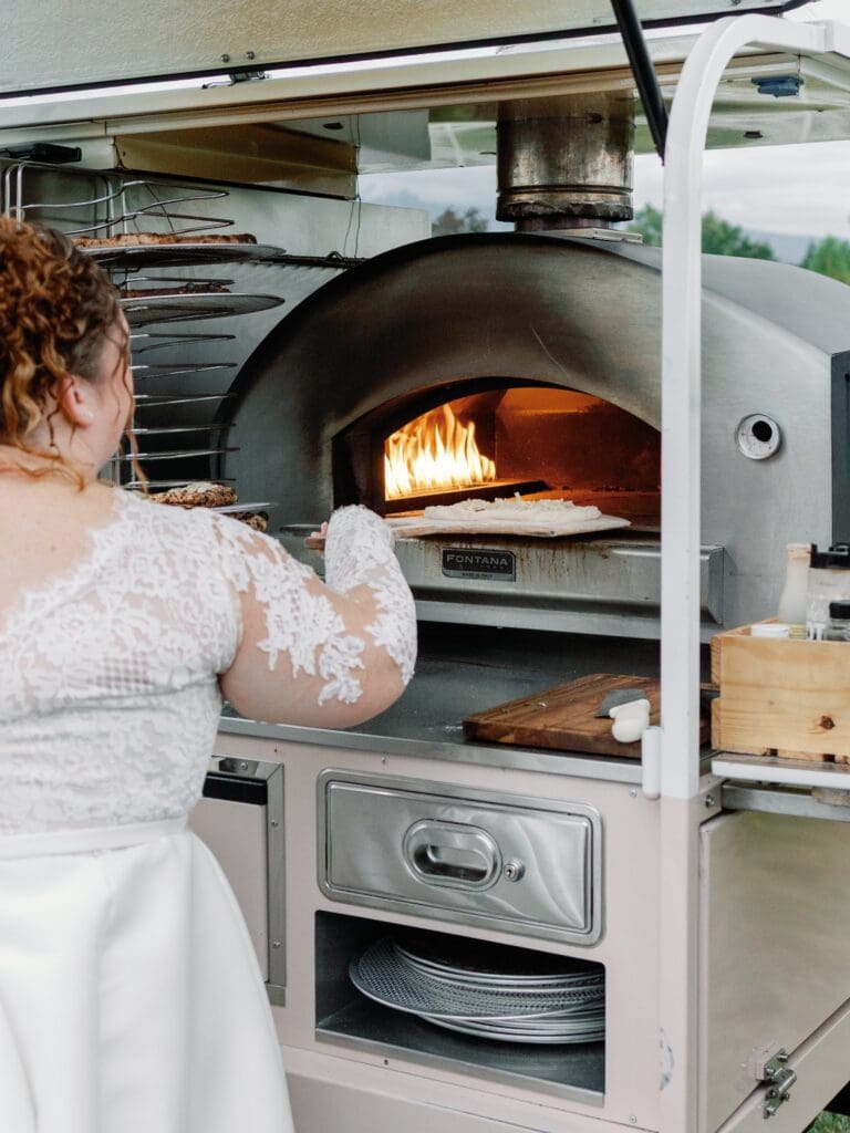 bride using a pizza oven at wedding reception